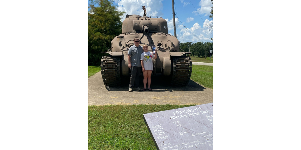 two people standing in front of a tank with the girl holding a Rox man