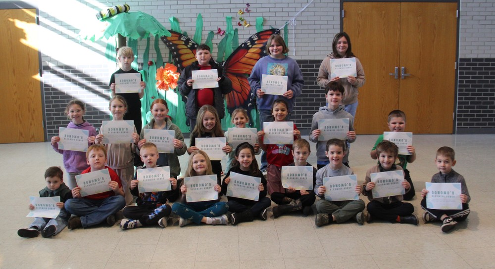 three rows of students sitting, kneeling, and standing holding certificates