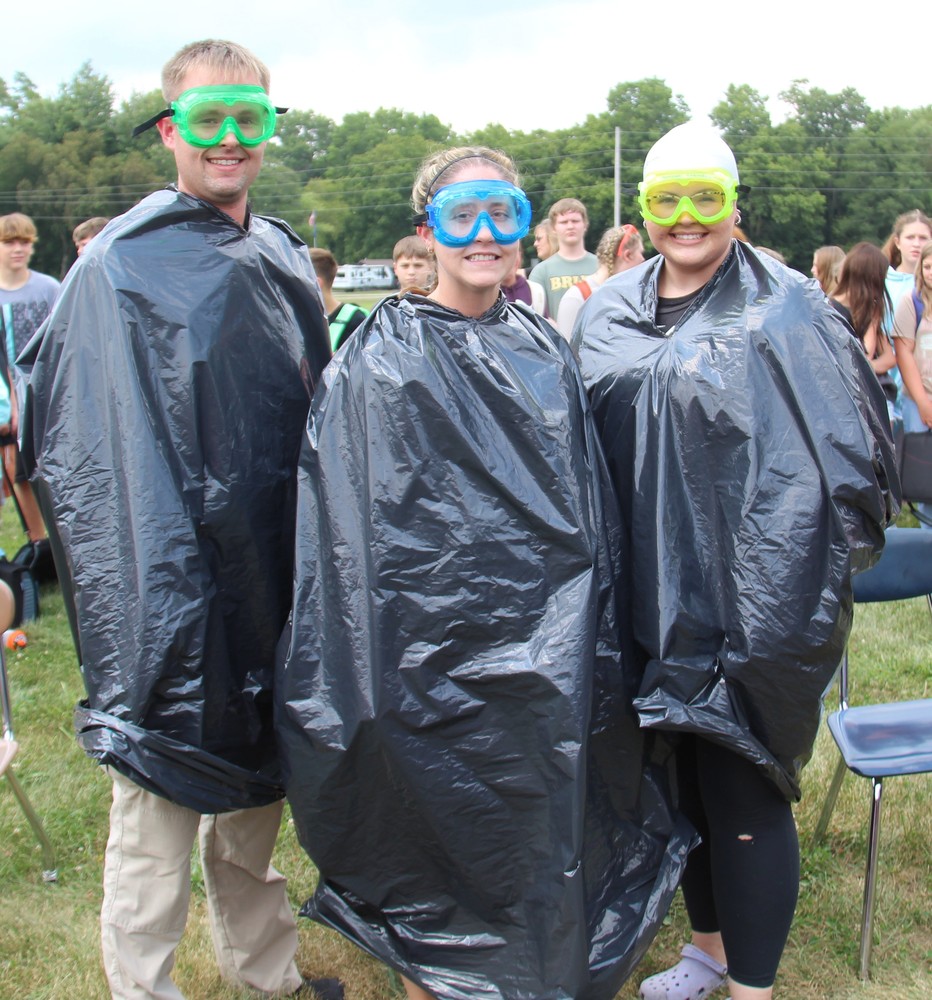 three people wearing trash bags and goggles