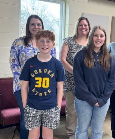 two students with two adults standing behind them