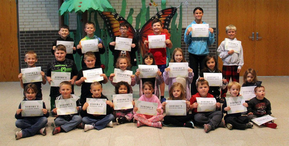 three rows of students sitting, kneeling and standing and holding certificates