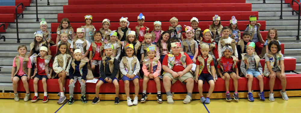 kindergarten students sitting on the gym bleachers and wearing their ABC vests