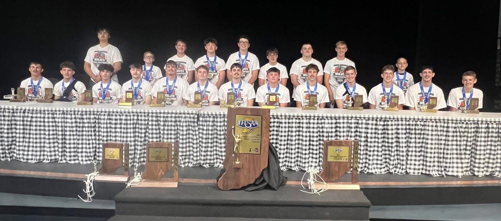 basketball players sitting or standing behind a table with their trophies in front