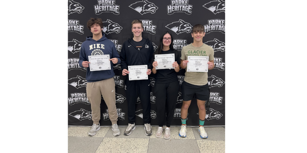 four students standing in front of a backdrop holding certificates