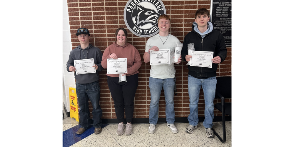 four students standing in a row holding certificates