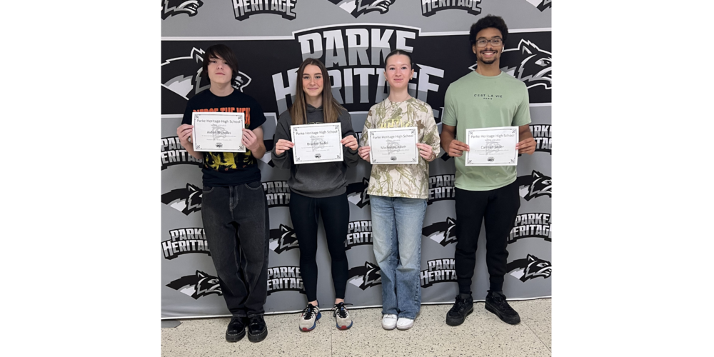 four students standing in front of a backdrop holding certificates