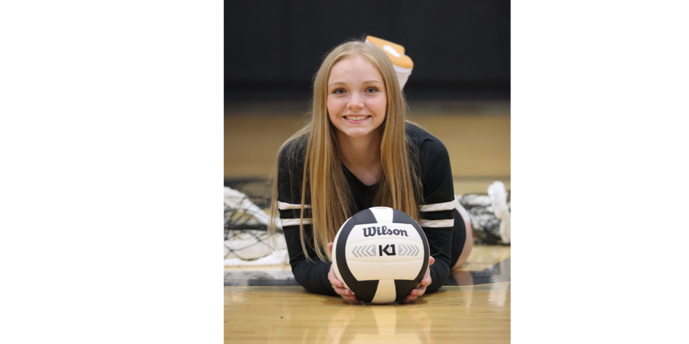 photo of Hallie Miller laying on the gym floor and holding a volleyball