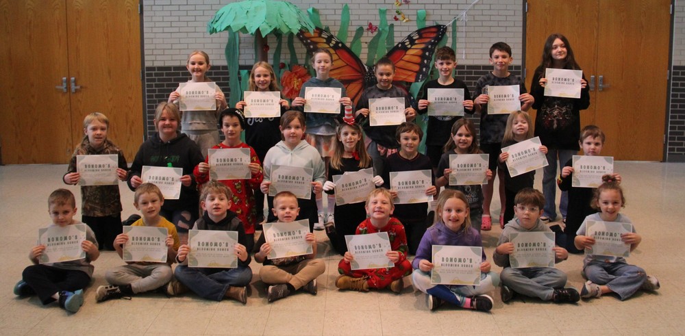 three rows of students standing, kneeling and sitting and holding certificates