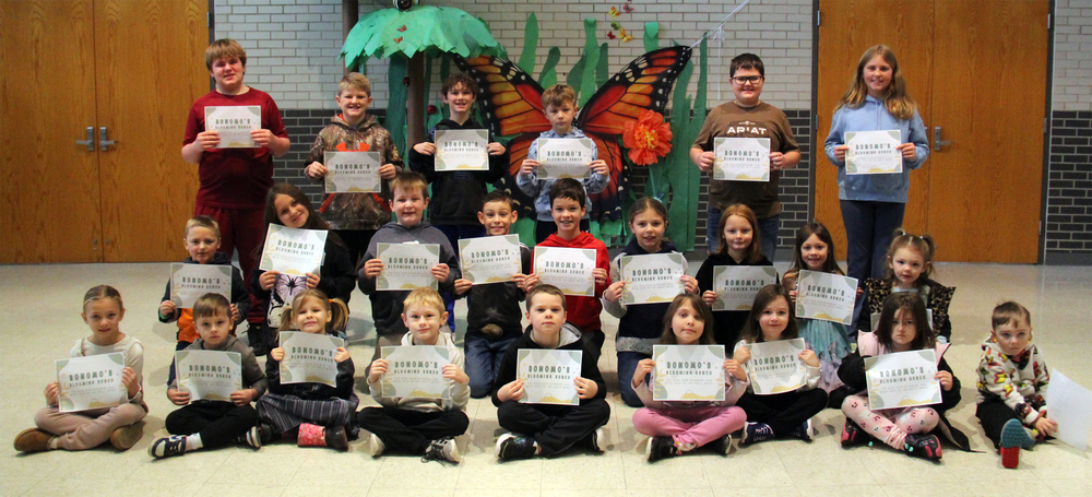 three rows of students sitting, kneeling and standing while holding certificates