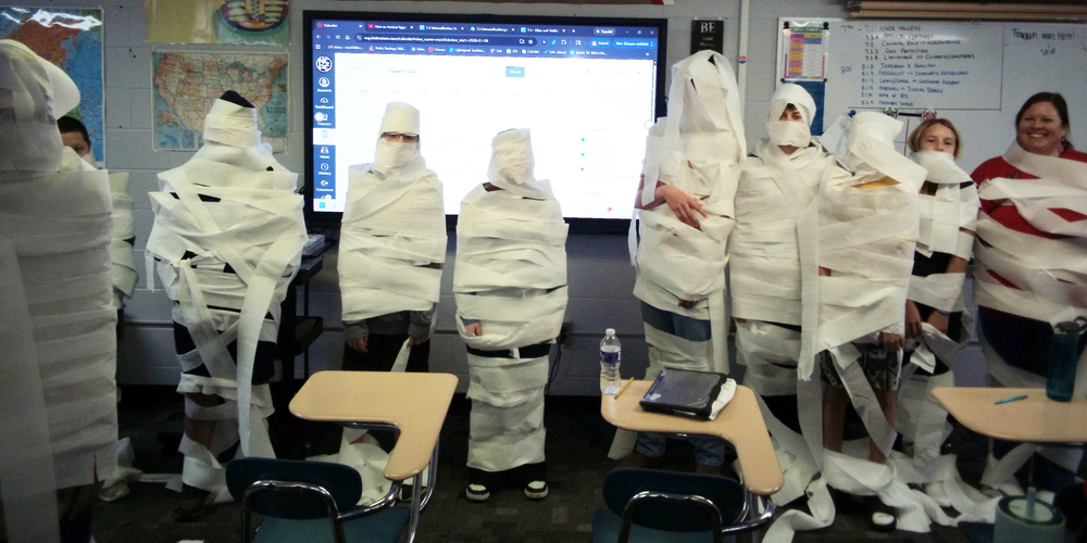 a group of students and staff wrapped in toilet paper as a part of the mummy unit