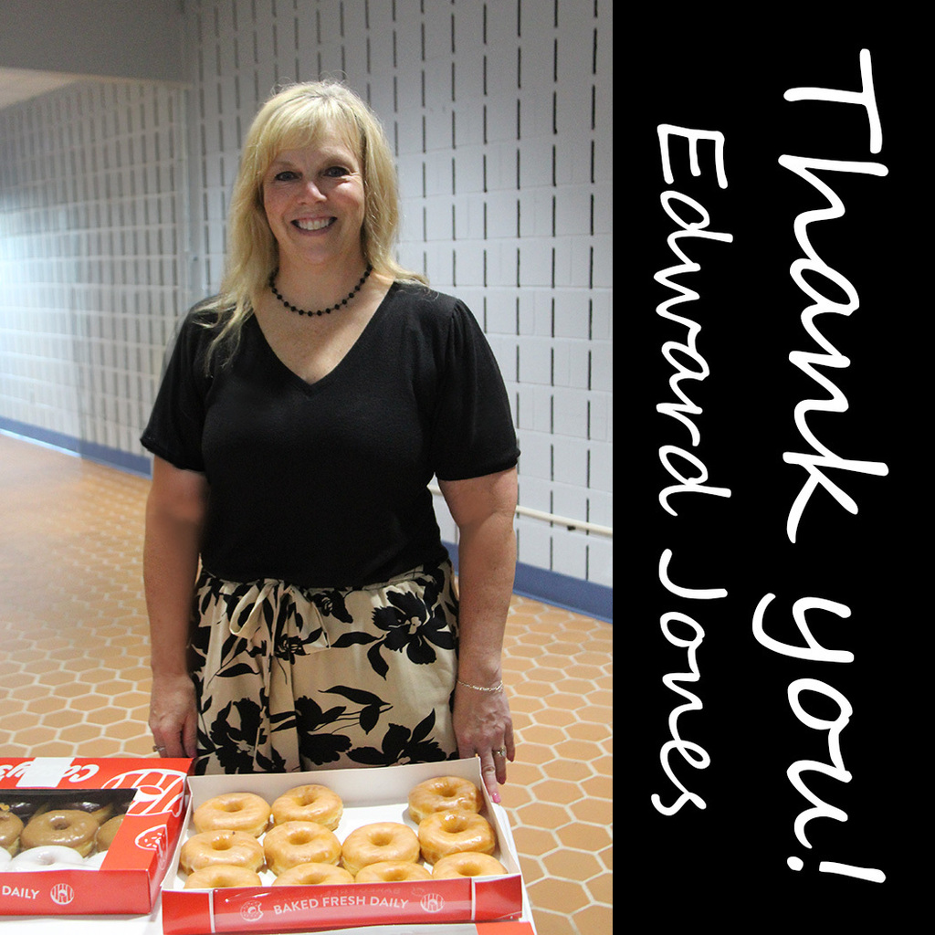A smiling woman stands behind boxes of donuts with a "Thank You!" message thanking Edward Jones for providing treats to NCPC School Corporation staff.