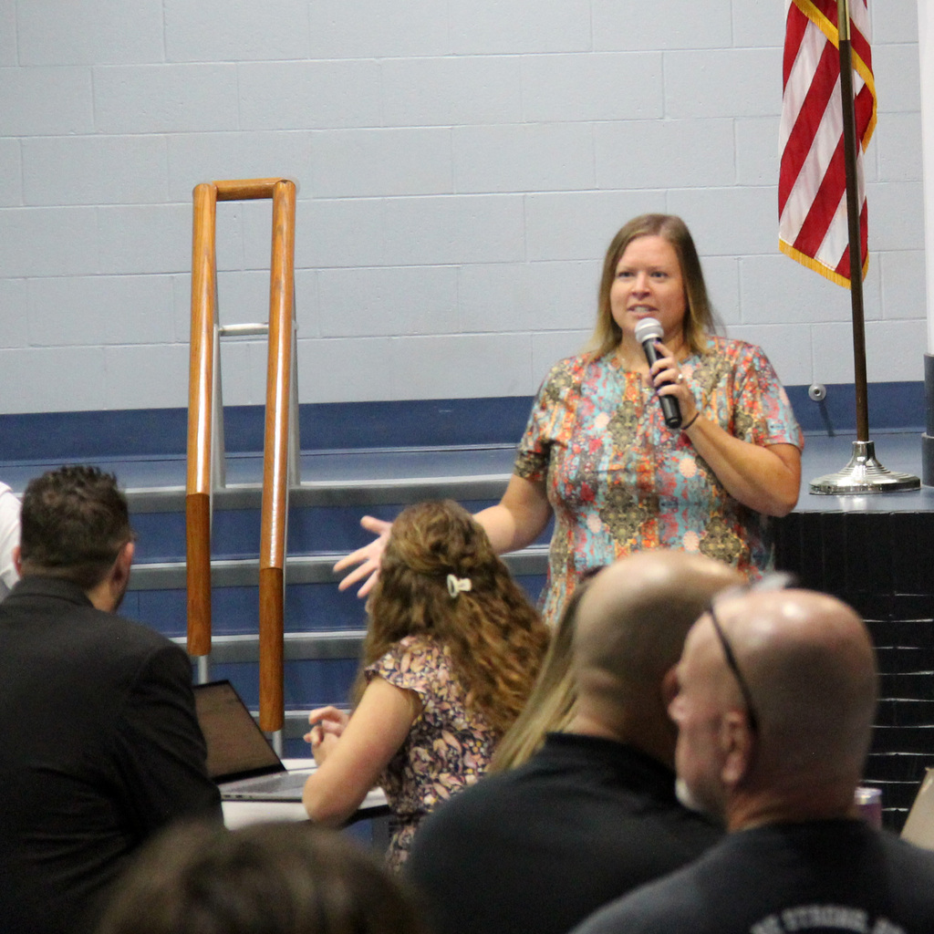 Middle School Principal speaks with a microphone while addressing colleagues during the school kickoff meeting.