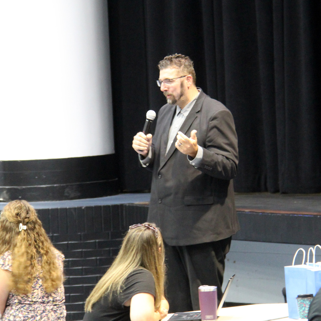 Highschool Principal shares information with colleagues during a back-to-school staff meeting.