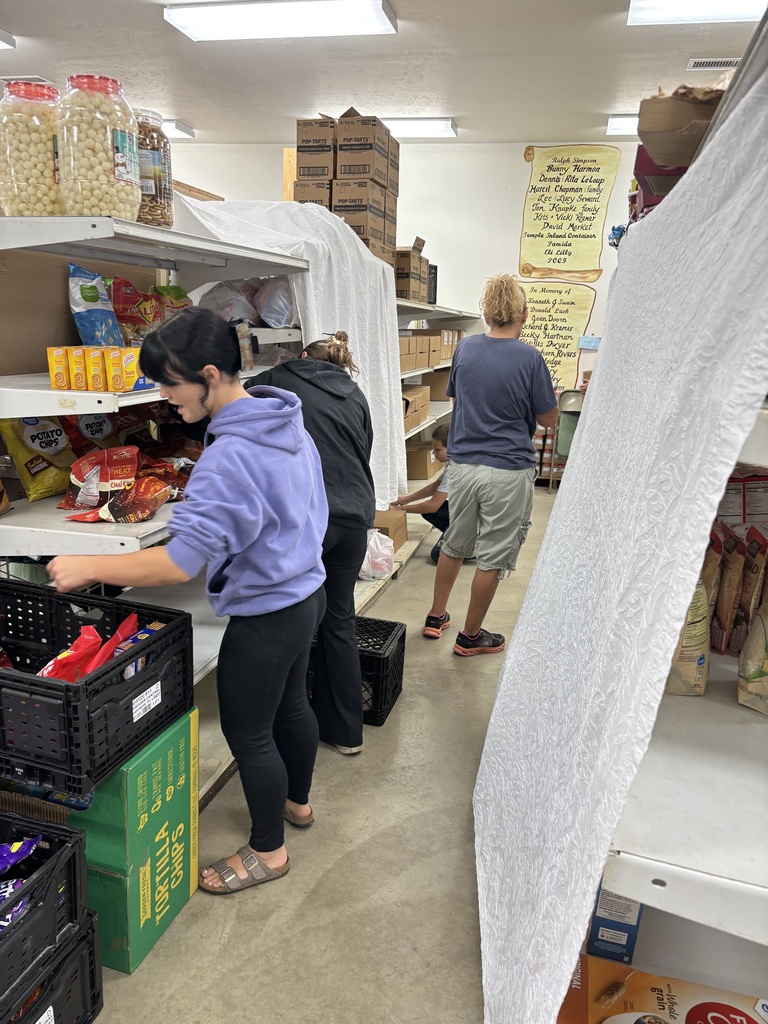 Photo of two students stocking shelves at the food pantry for volunteer hours. 