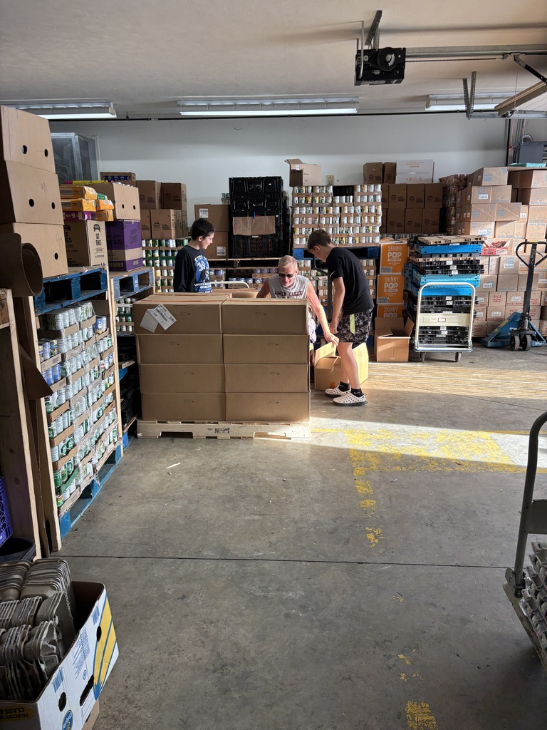 Photo of two students and an adult unpacking boxes at the food pantry for volunteer hours. 