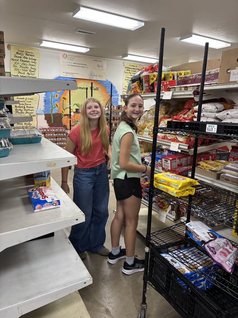 Photo of two students stocking shelves at the food pantry for volunteer hours. 
