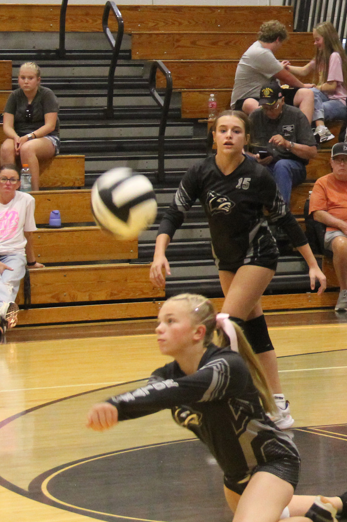 One player bumping the ball while another player runs toward her to help if needed. 