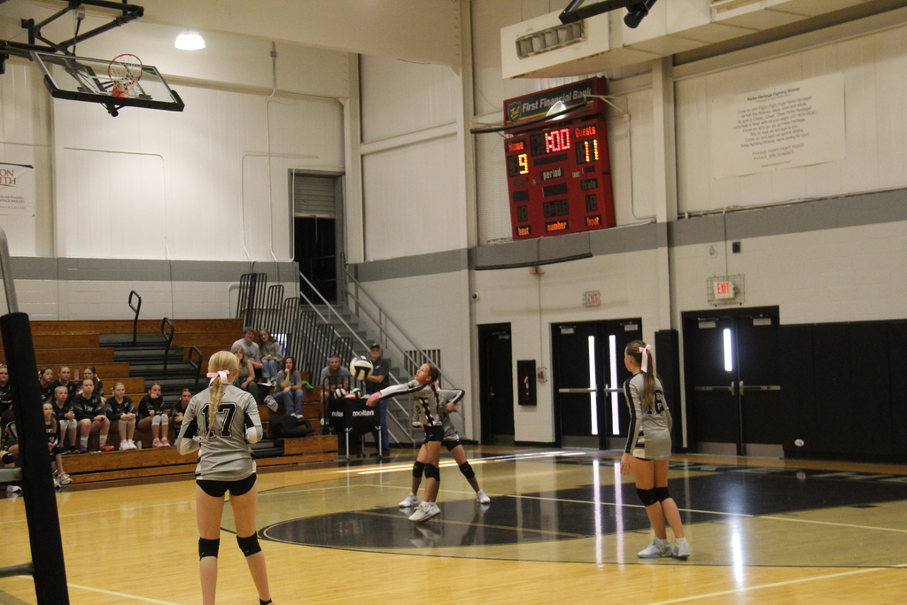 Volleyball Player bumping the ball will others stand in anticipation.