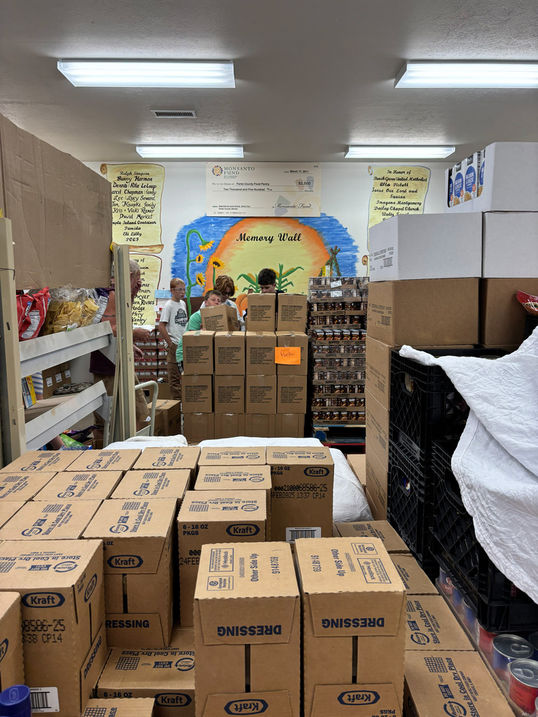 Four students grabbing boxes to help stock shelving.