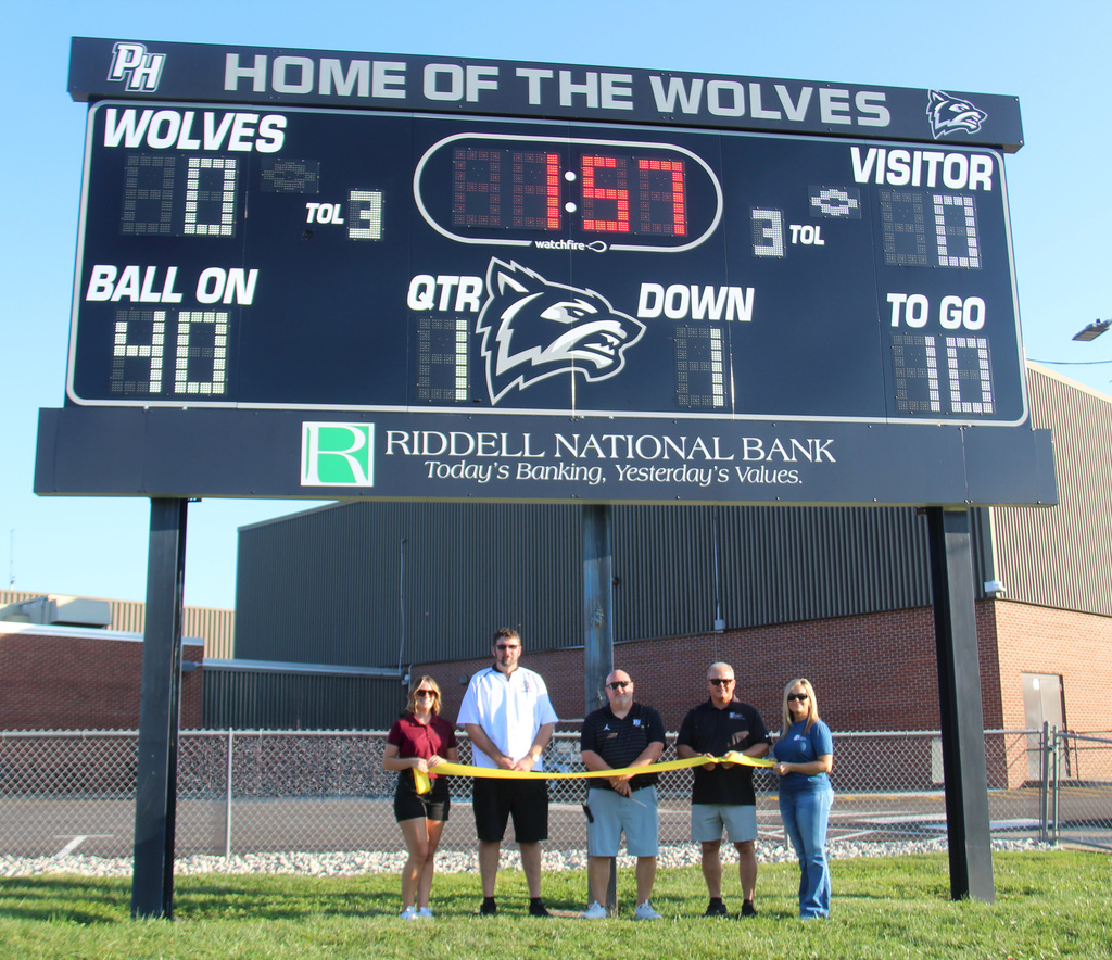 Five individuals standing underneath the new Scoreboard during the ribbon cutting ceremony.