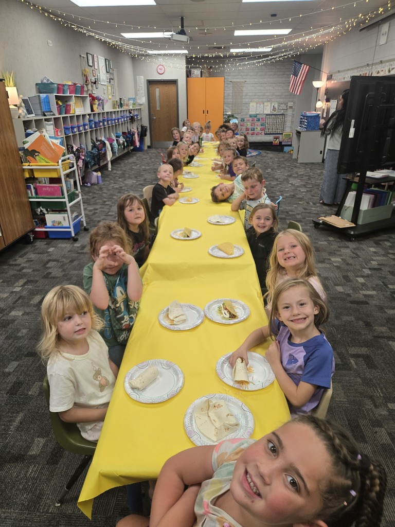 All the Transitional kindergarten class sitting at a very long table posing with their soft taco plate in front of them for Foodie Friday.