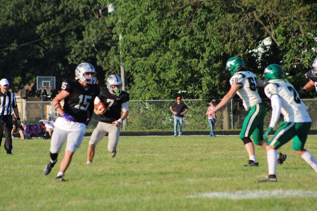 Parke Heritage football players in black uniforms advance down the field with the ball while opponents in green and white uniforms move to defend.