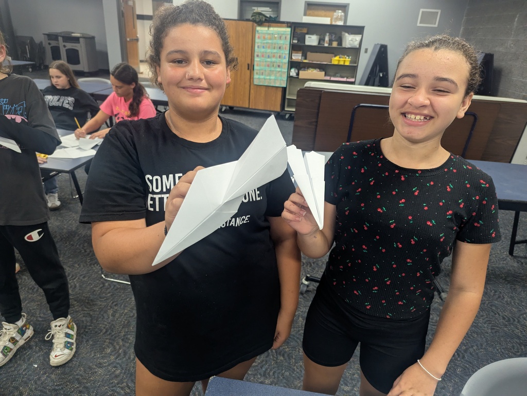 2 girls holding their paper airplanes.