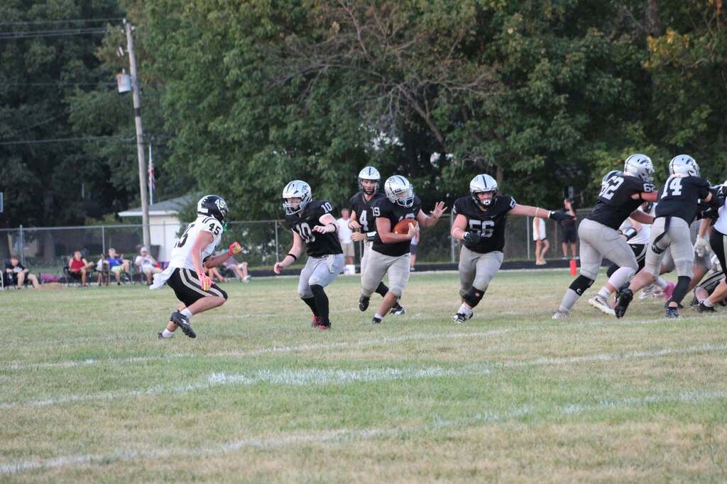 Football player carrying the ball while teammates block defenders during a game