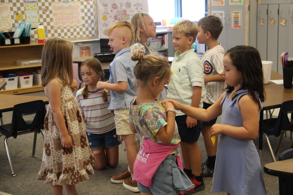 Students mingling while sticking sticky note to each other for a classroom activity they are doing. 