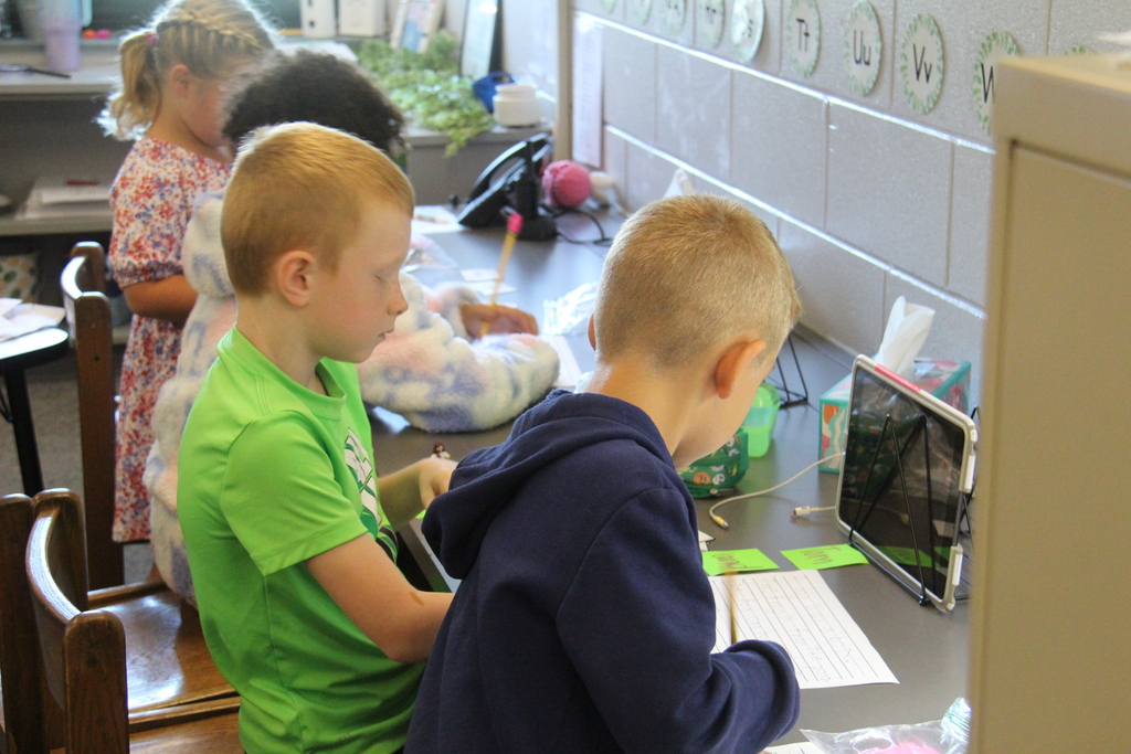 Students sitting at a counter in the classroom working on writing activities. 