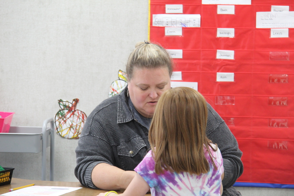 Teacher helping a little girl with her work at the table. 