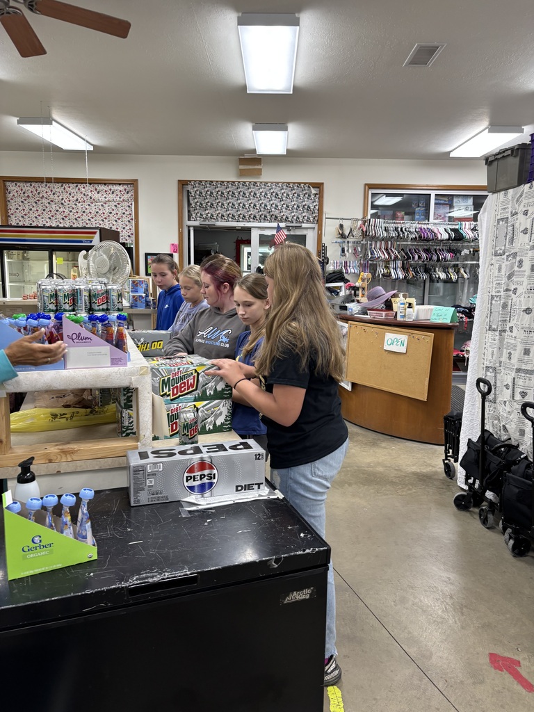 Middle school students work together inside a food pantry, organizing and handling donated food items as part of their volunteer service.