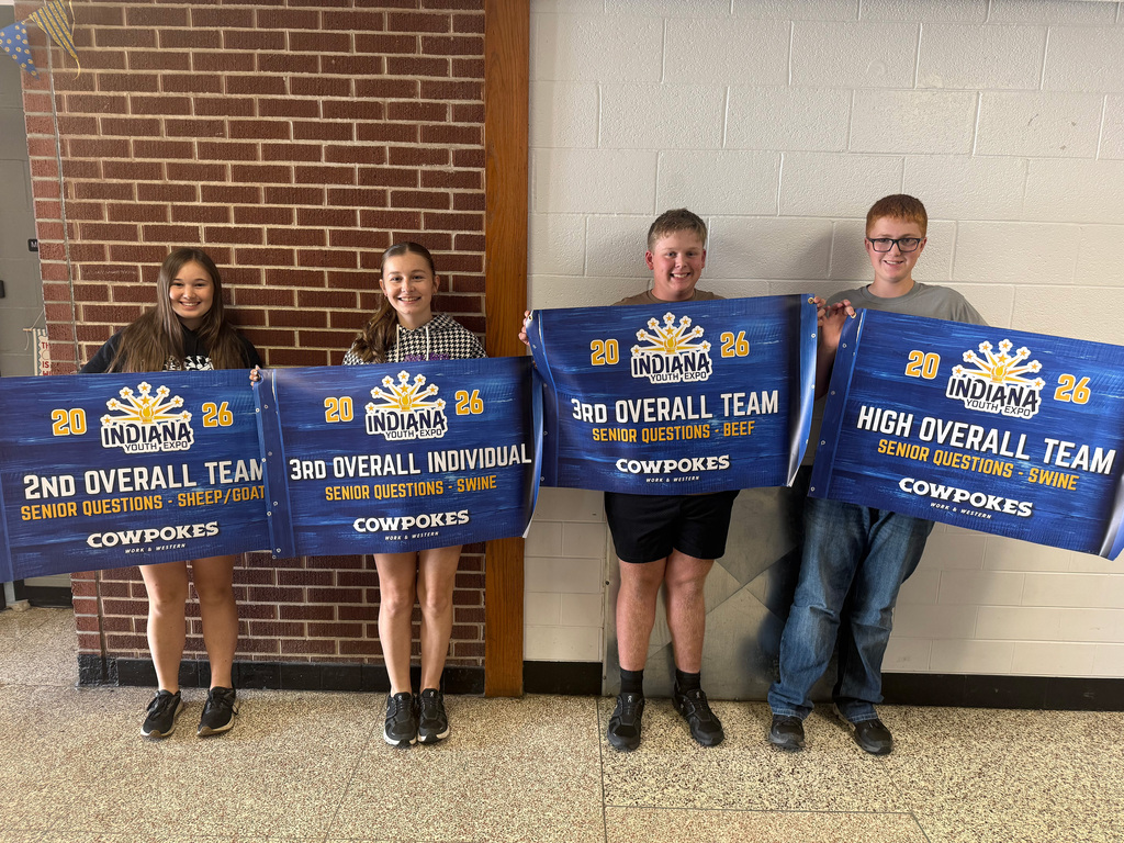 Four youth livestock judging participants stand indoors holding award banners from the 2026 Indiana Youth Expo. The group earned 2nd Overall Team in Senior Questions–Sheep/Goat, 3rd Overall Individual in Senior Questions–Swine, 3rd Overall Team in Senior Questions–Beef, and High Overall Team in Senior Questions–Swine.