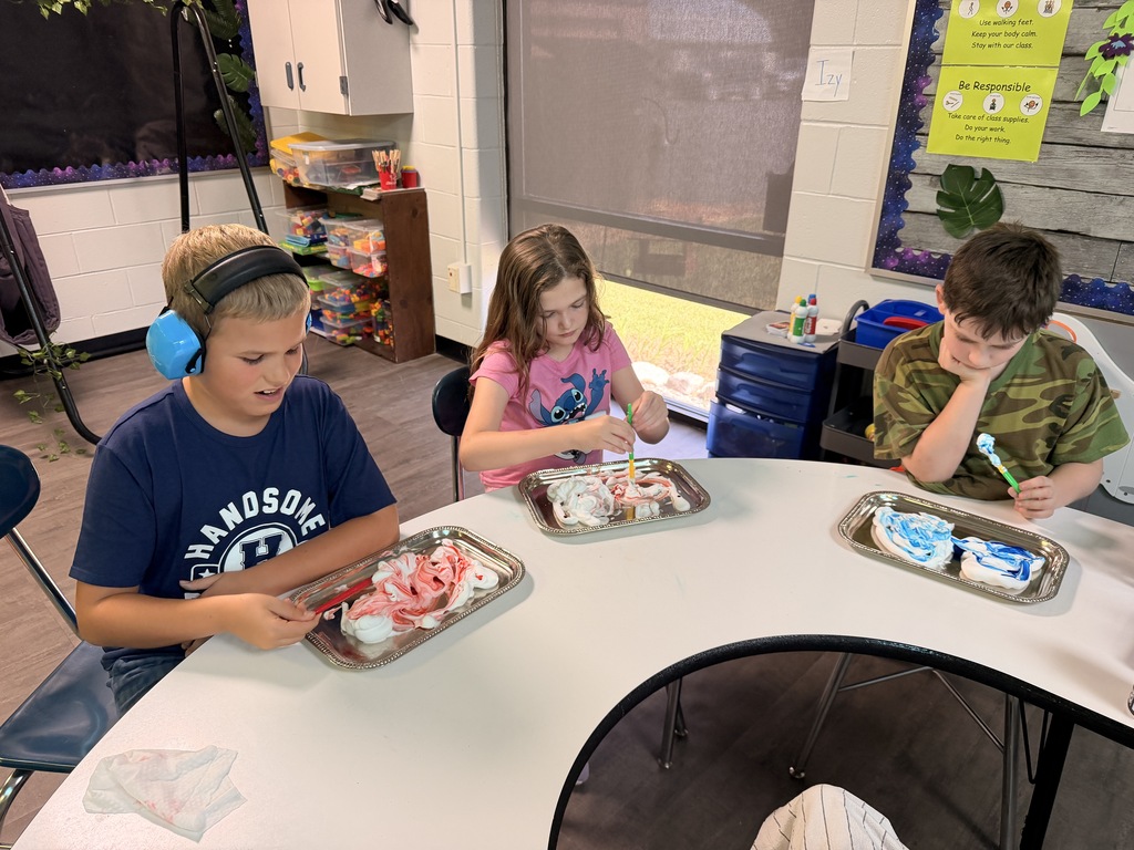 3 students working with shaving cream and red, yellow, and blue food coloring for fine motor skills learning. 