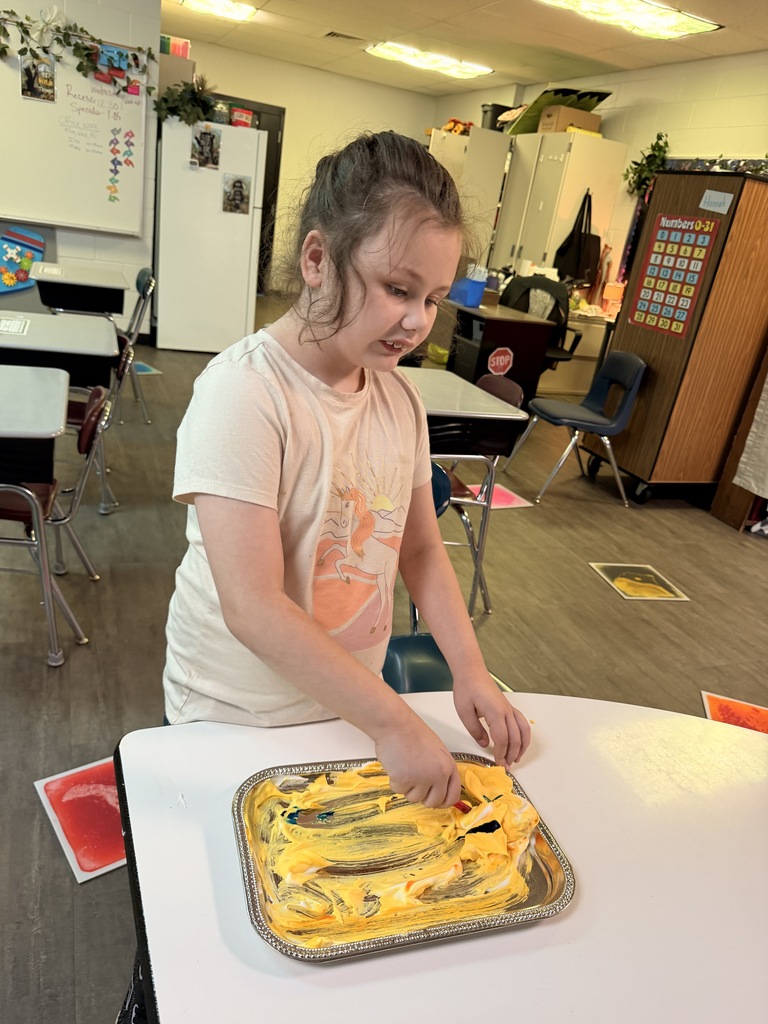 A student working with shaving cream and yellow food coloring during fine motor skills learning. 