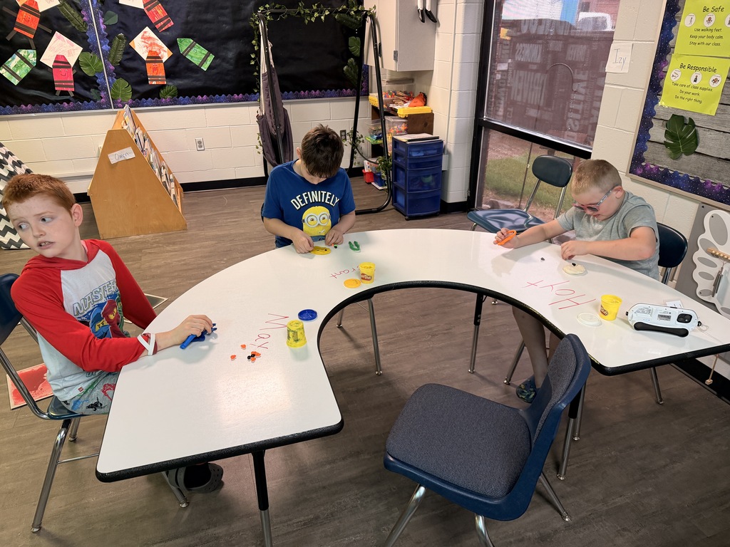3 students playing with playdoh during fine motor skills learning. 