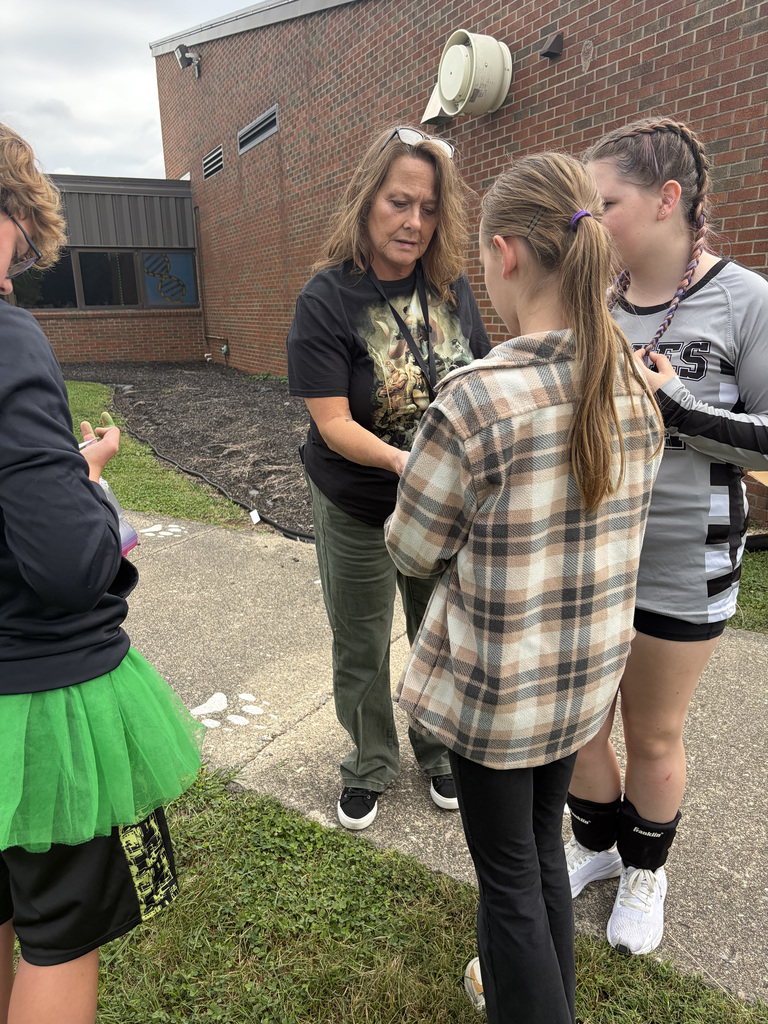 A parent and 2 students collaborating about tie-dying their shirts at the Bindi BBQ.