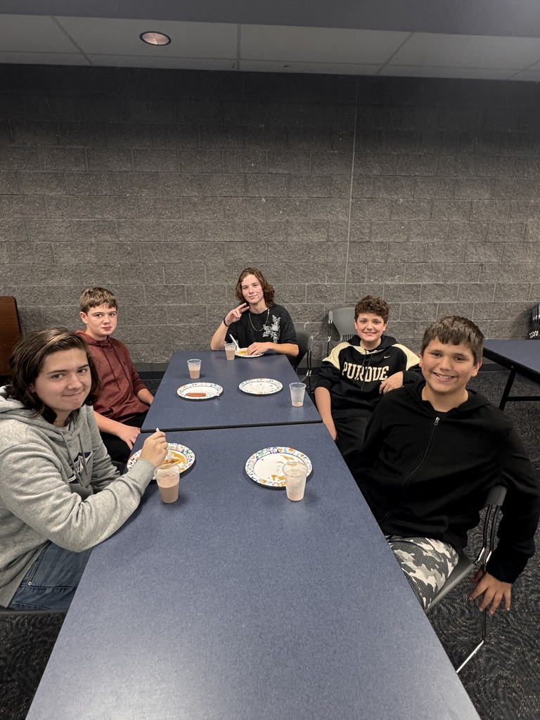 5 students smile for a photo with their pancake plate in front of them. 