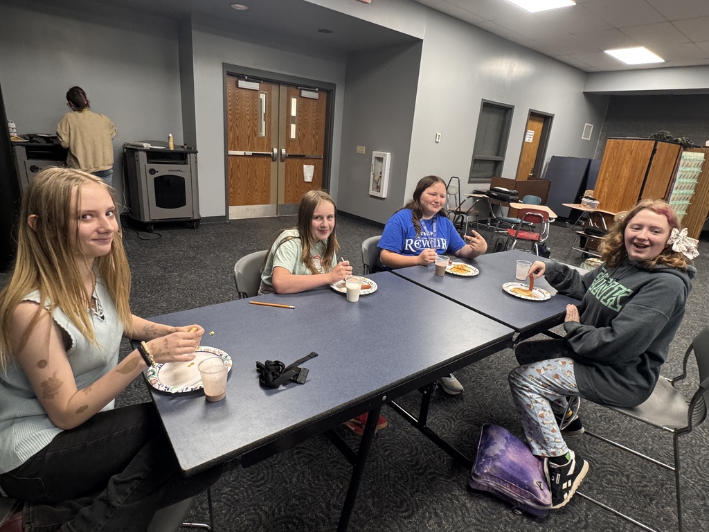 4 students smile for a photo with their pancake plate in front of them. 