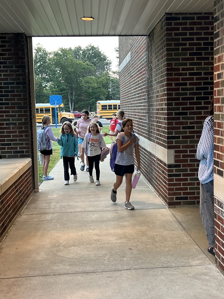 Students walking up the sidewalk, after their high fives for High Five Friday, to enter the building.