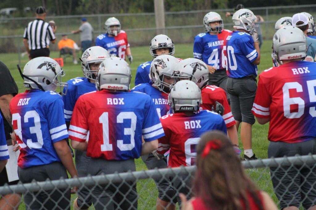 PHMS Football Players standing around in their Rox Warriors Jerseys (half red and half blue) during the Throwback game.