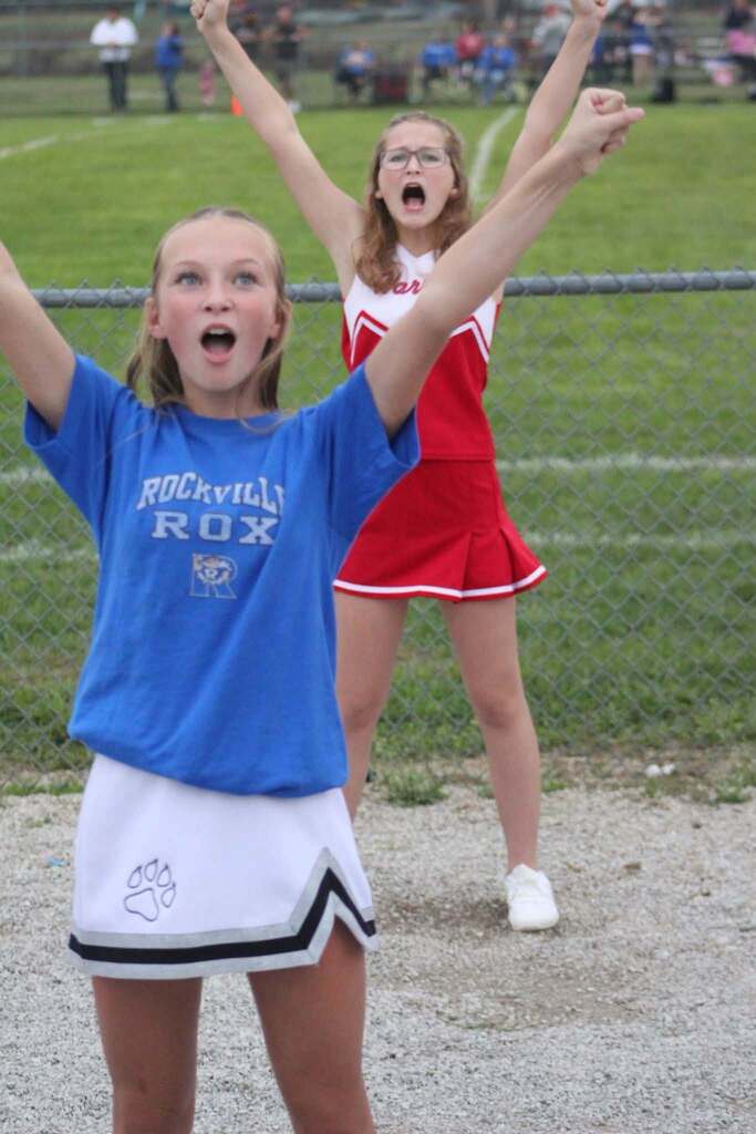 Cheerleader in Rockville ROX uniform and Cheerleader in Turkey Run Warriors uniform, cheering at the Throwback Game. 