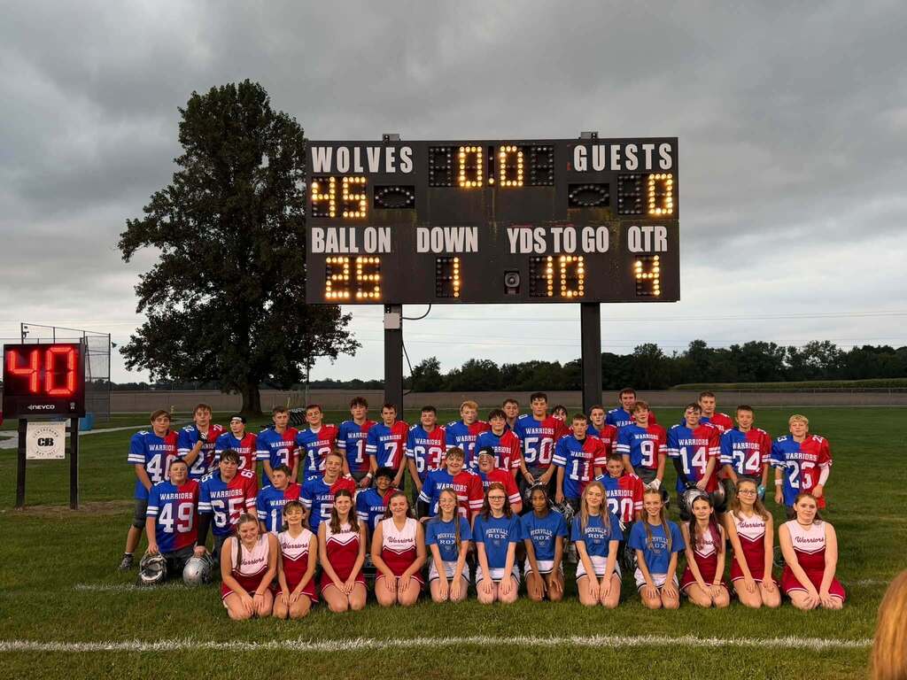 PHMS Cheerleaders and Football Players posed for a photo in front of the scoreboard with a score of Wolves 45 and Guests 0. 