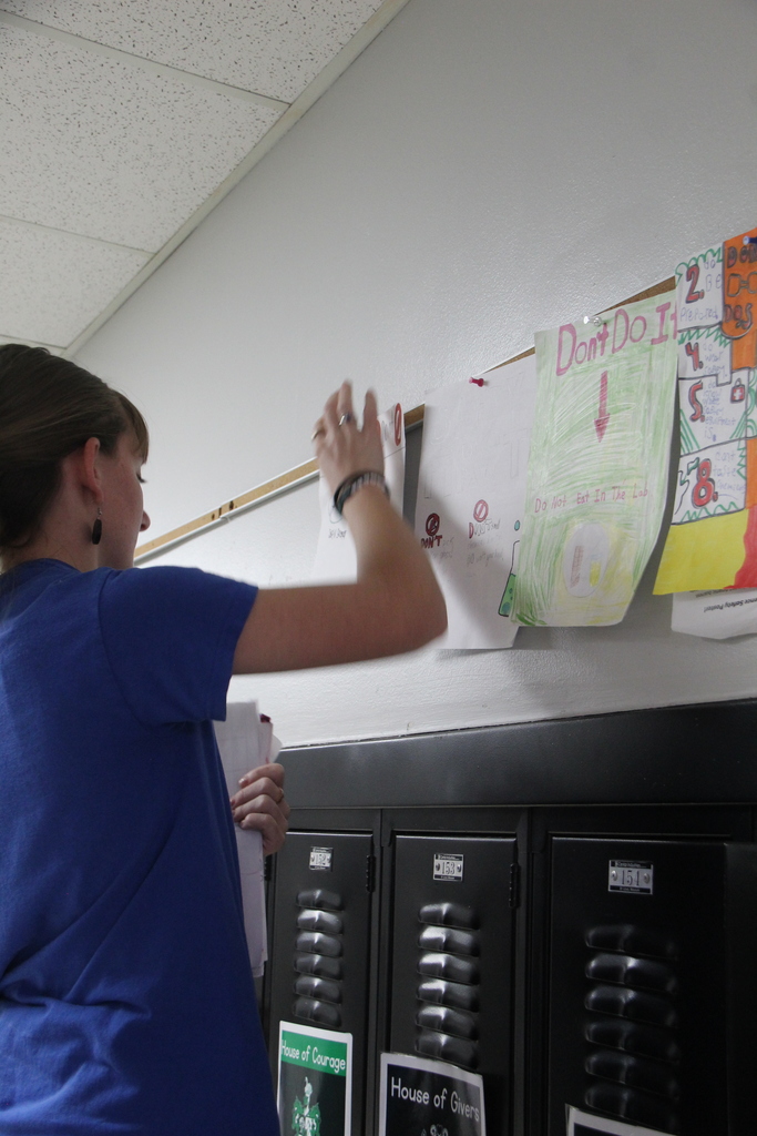 Education Professions student hanging projects on the cork strip on the wall above the lockers. 