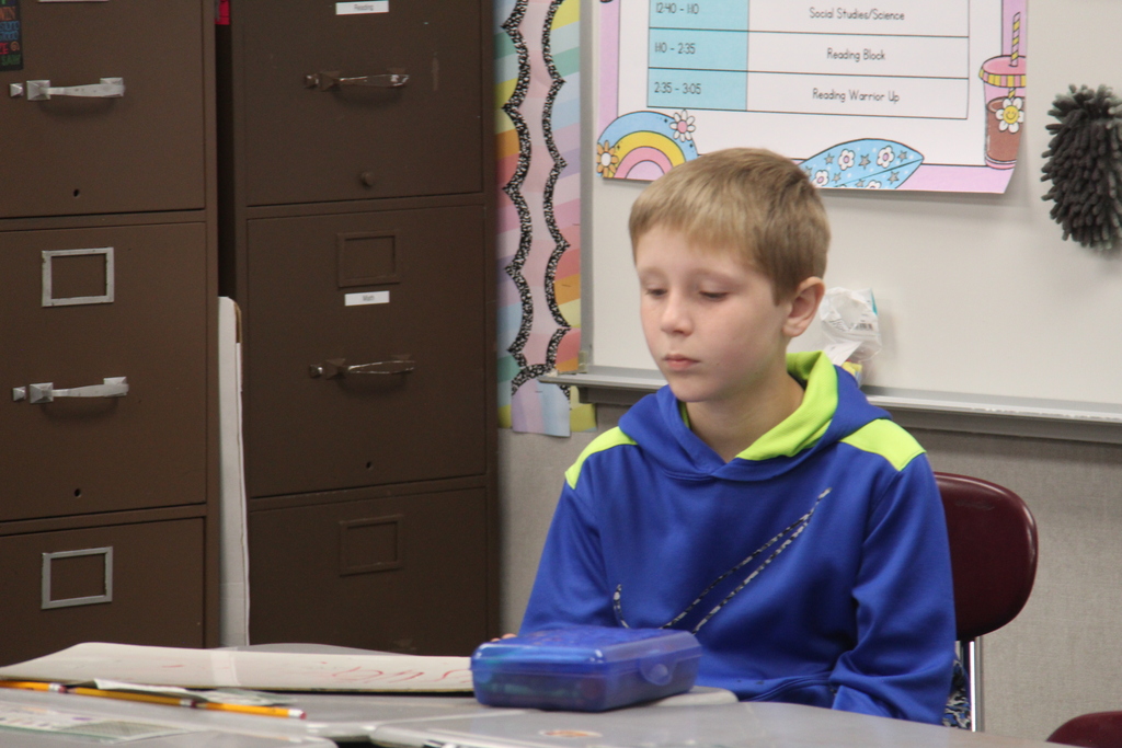 A boy examining his white board thinking about how to do the math problem.