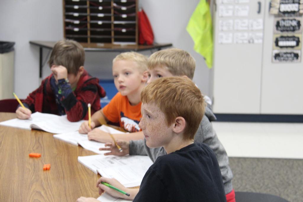 4 students listening to the teacher, teach math, with their notebooks and pencils in front of them!