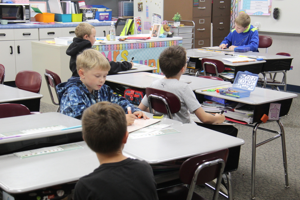 6 boys listening and working on their white boards for a math lesson. 