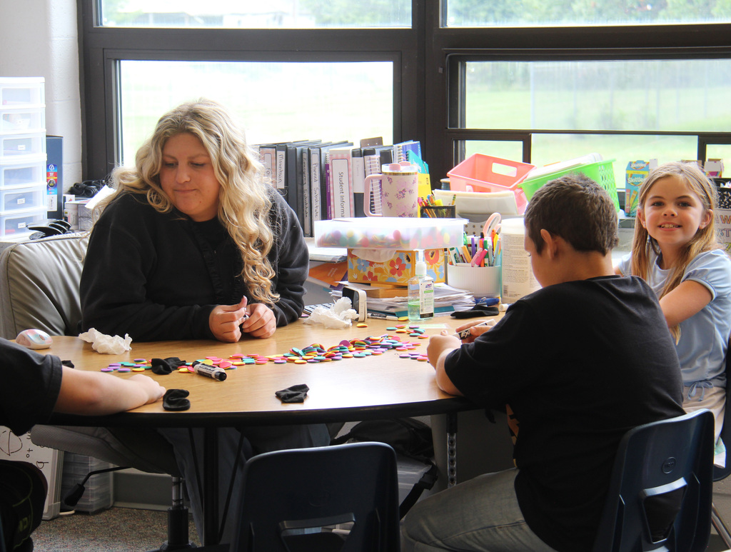 RES 3rd grade teacher sitting at a half moon table helping the students across from her.