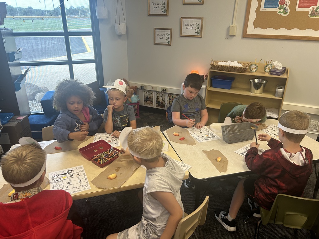Students sitting around a table working on worksheets while eating their delicious apples. 