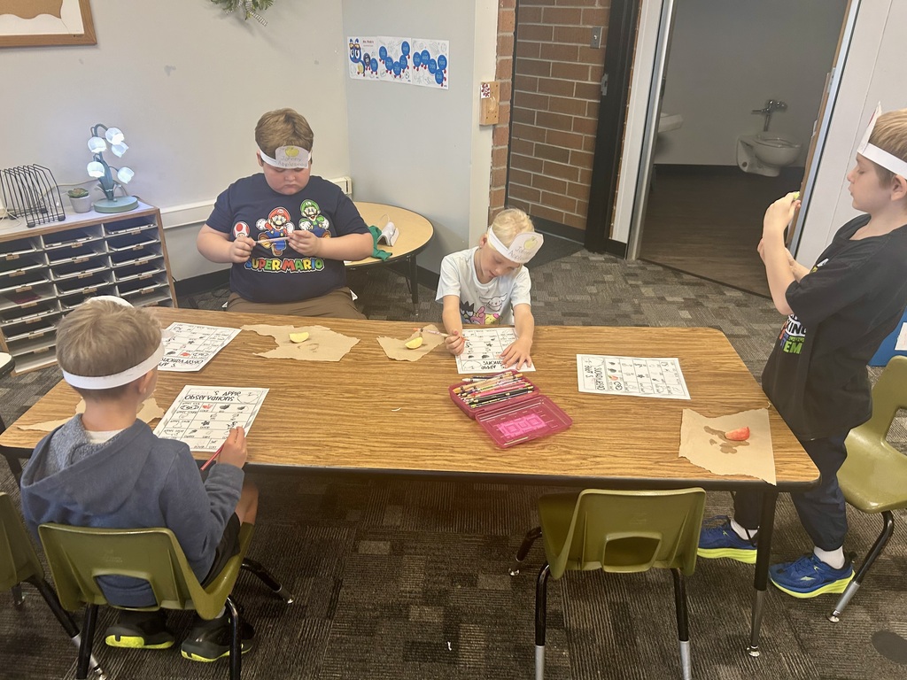 Students sitting around a table working on their worksheets while eating their delicious apples. 